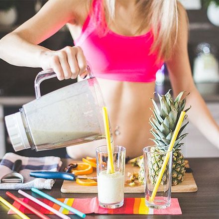 Woman blending a fresh fruit smoothie in her kitchen