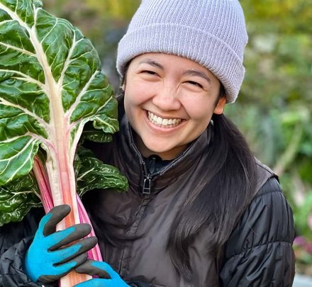 Smiling woman holding a bunch of fresh rainbow chard